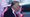 A photo of Donald Trump from the side, walking past a car.